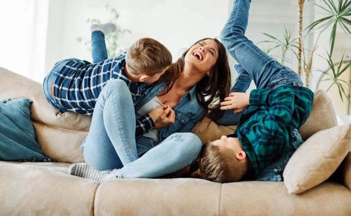 Engage with your kids like this mom and two sons laughing and playing on couch