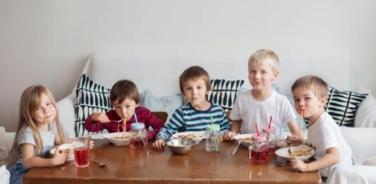 Big family with multiple kids eating cereal at a coffee table
