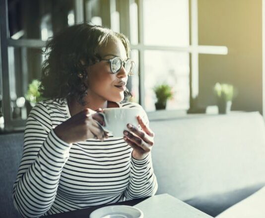 Woman holding a coffee cup looking contently to the side happy without a friend squad