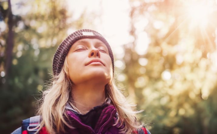 Woman in forest with eyes closed seeming content that her parent is dead