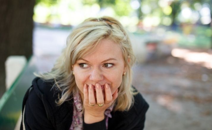 socially anxious woman looking shy with her mouth covered by her hand