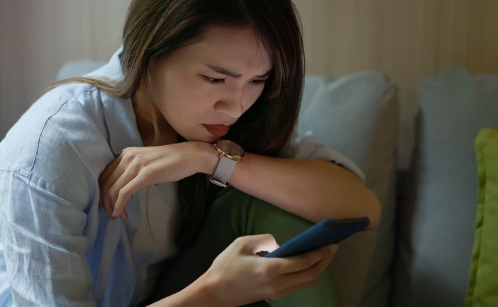 woman staring at phone when being stalked online