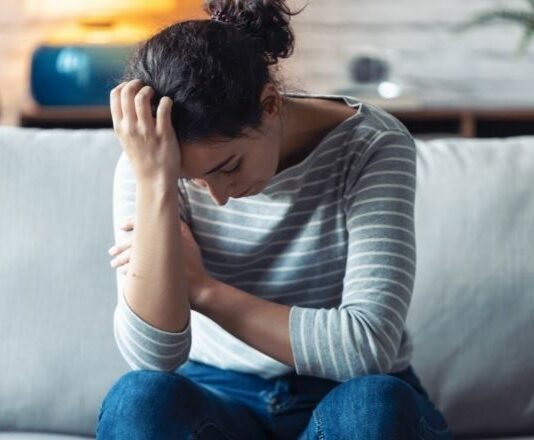 woman with head down on one hand experiencing anxiety