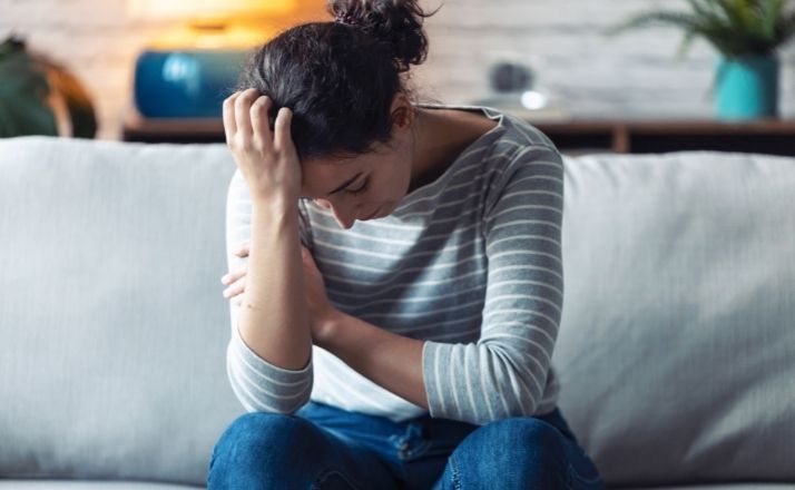 woman with head down on one hand experiencing anxiety