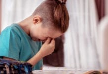 Cute schoolboy appearing to be frustrated while doing his homework