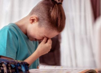 Cute schoolboy appearing to be frustrated while doing his homework