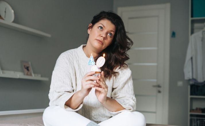 woman holding cupcake with a #4 and #0 candle for forty years old