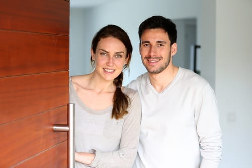 Happy couple opening new home entrance door