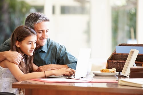 Father And Teenage Daughter Looking At Laptop Together