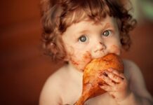 Messy little one eating a turkey leg showing how toddlers change Thanksgiving