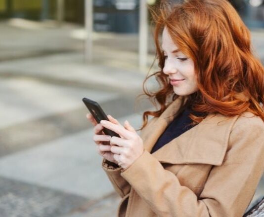 Woman smiling and creating better tweets on Twitter on her cellphone