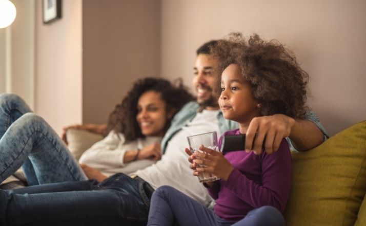 Black family sitting on the couch watching tv after they cut the cable cord