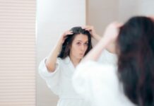 Woman looking in mirror finding gray hair