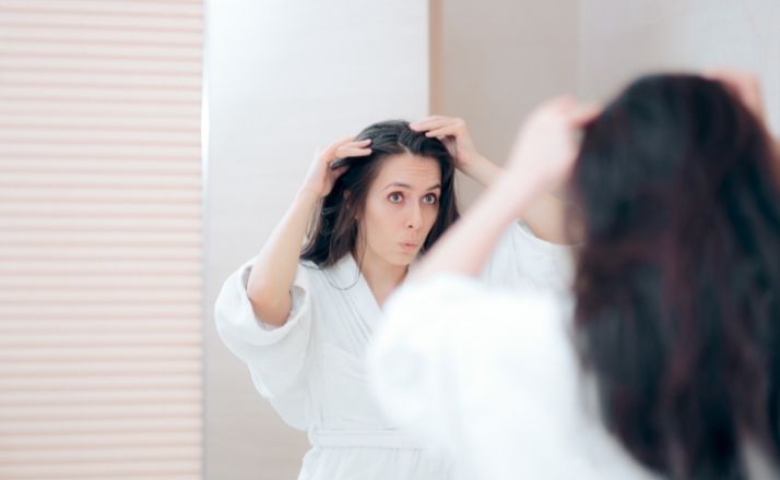 Woman looking in mirror finding gray hair