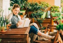 woman reading a book while sitting on a porch surrounded by plants on a mommy vacation