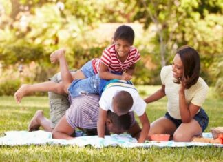 Family laughing and playing on a picnic blanket while on spring break