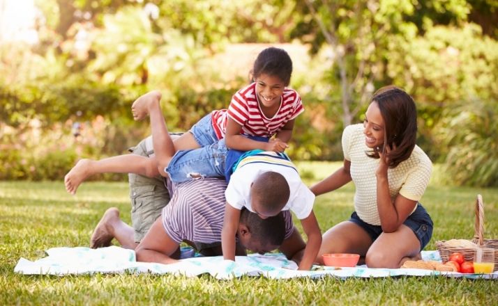 Family laughing and playing on a picnic blanket while on spring break