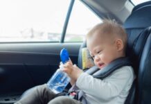 Toddler in car seat holding a sippy cup