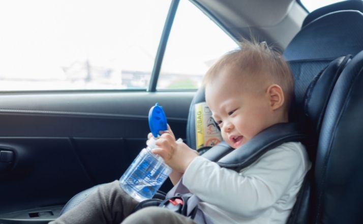 Toddler in car seat holding a sippy cup