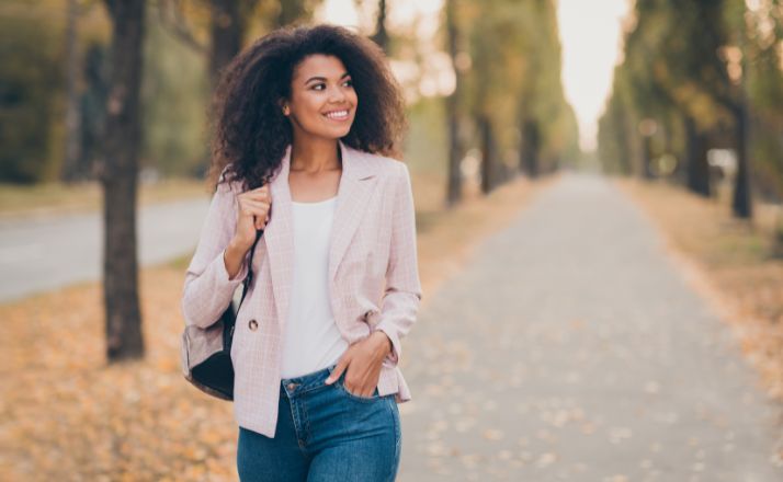 woman walking in her fashionable wardrobe staples of dark jeans, white shirt, and blazer