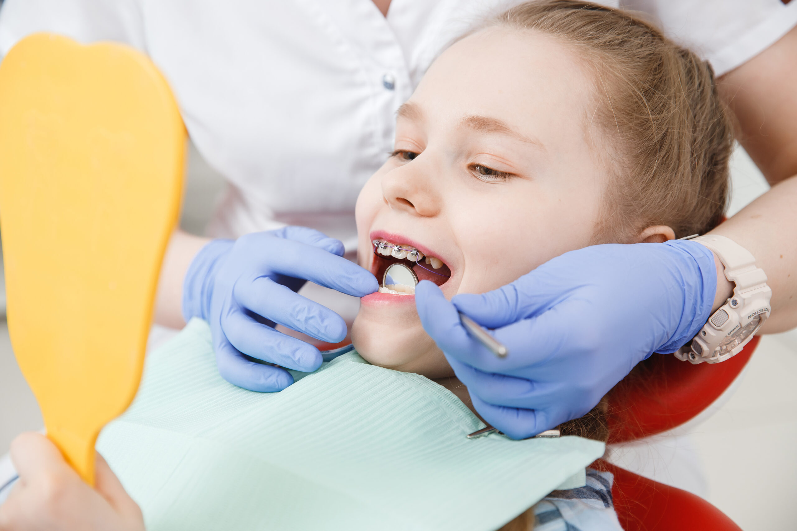 girl with braces at dentist getting her teeth checked