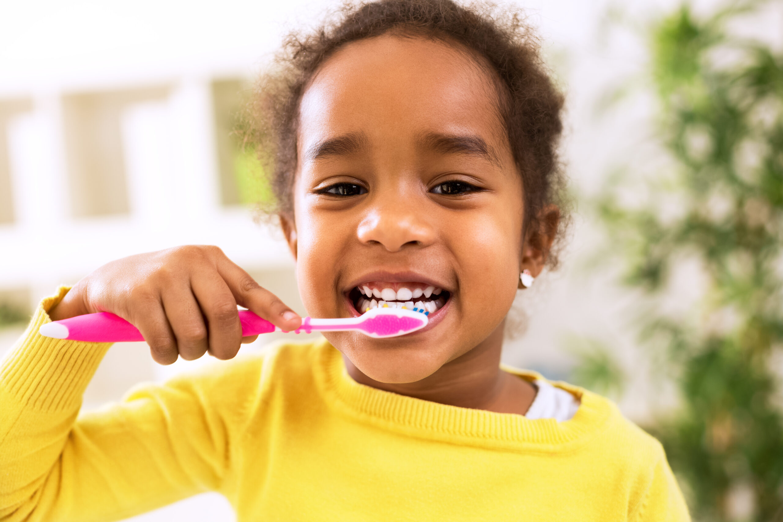 black girl brushing her teeth with pink toothbrush