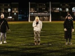 women standing in a football field screaming