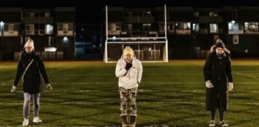 women standing in a football field screaming