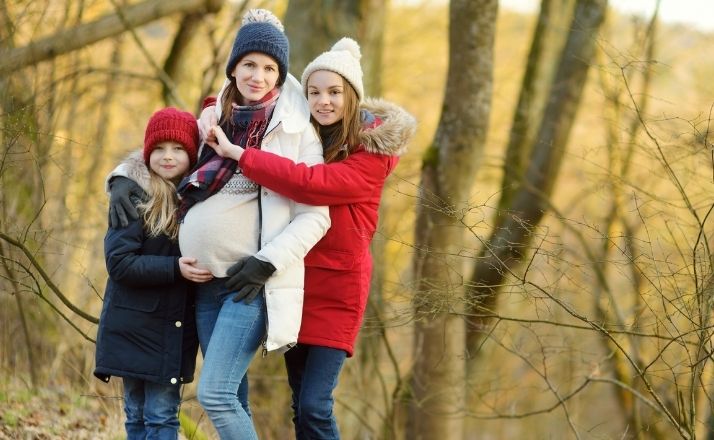 geriatric pregnancy pregnant mom and two daughters standing in nature