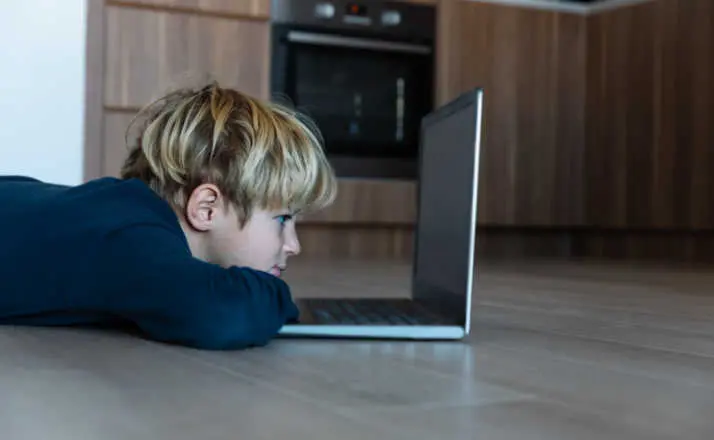 kid looking at computer at home, online learning and remote education kids' mental health