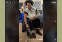 Screenshot of a man sitting on a bed with a watermelon plastic wrapped to his belly.