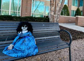 creepy doll on bench in front of city building