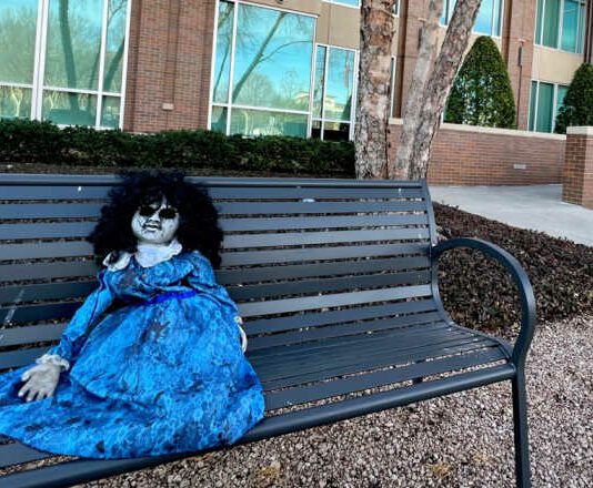 creepy doll on bench in front of city building