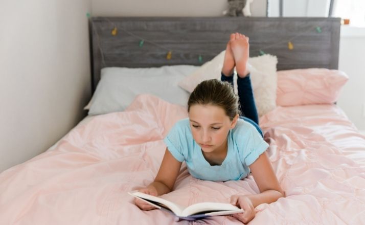 young girl on bed reading book