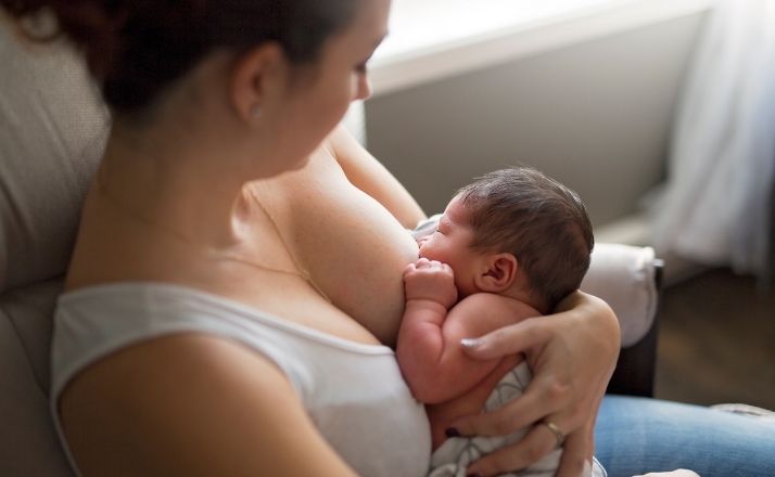 mom sitting in chair breastfeeding baby with lip tie