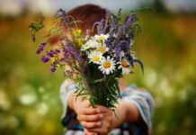 child holding wildflowers out as an example of random acts of kindness