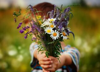 child holding wildflowers out as an example of random acts of kindness