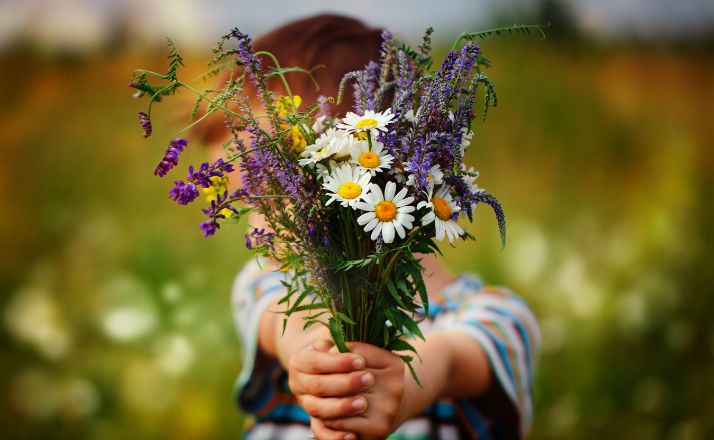 child holding wildflowers out as an example of random acts of kindness