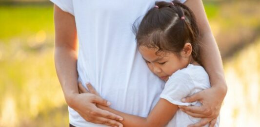 sad daughter hugging her dad while showing signs of trauma bonding