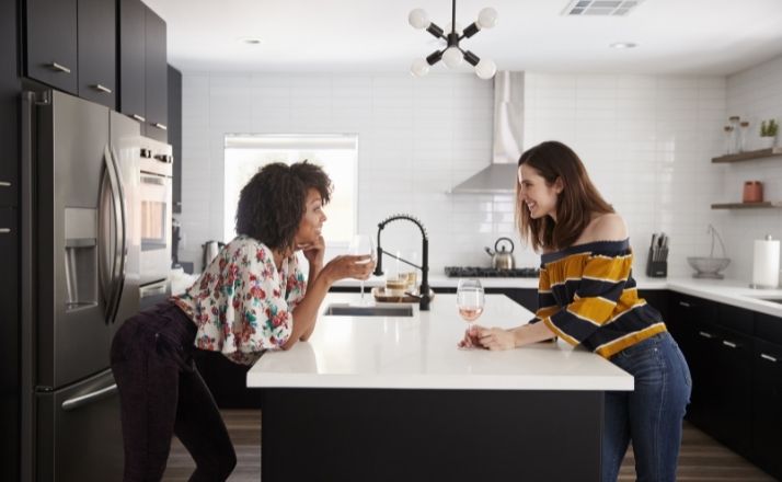 two women standing over kitchen counter smiling and talking