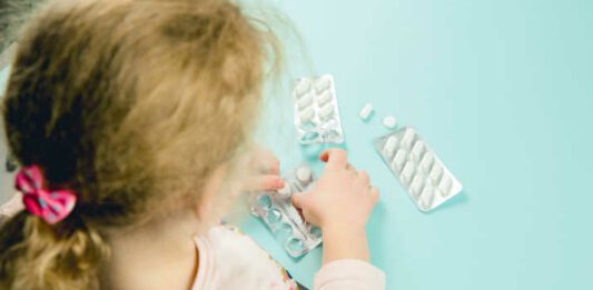 Young child play alone with pills tablets at home. Keep away from children reach concept. No medicine cabinet, raise awareness.