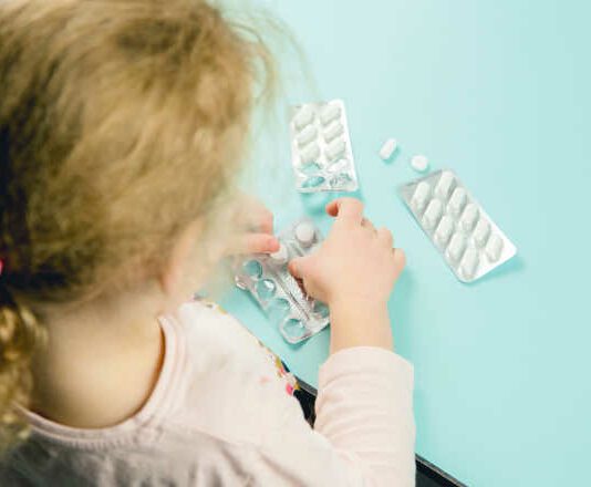 Young child play alone with pills tablets at home. Keep away from children reach concept. No medicine cabinet, raise awareness.