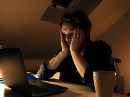 Young man working from home tired and stressed looking at his laptop