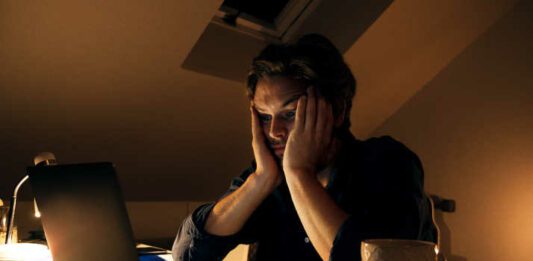 Young man working from home tired and stressed looking at his laptop