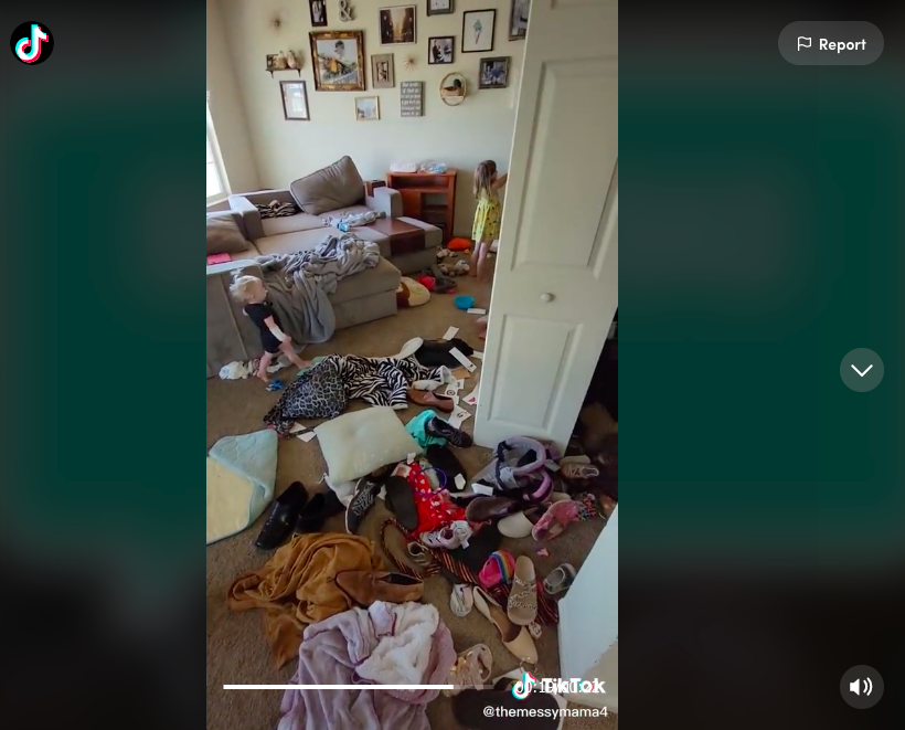 Screenshot of TikTok video by @themessymama4 showing her living room covered in clothing and toys, two children are in the background