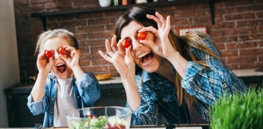 Mom and daughter holding tomatoes to their eyes being silly as they learn to stop caring what others think
