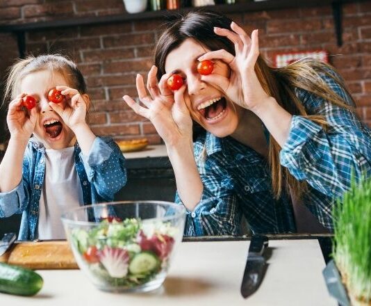 Mom and daughter holding tomatoes to their eyes being silly as they learn to stop caring what others think