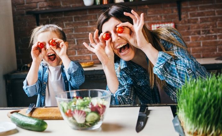 Mom and daughter holding tomatoes to their eyes being silly as they learn to stop caring what others think