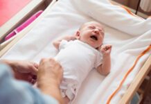 baby crying on a changing table with mom nearby as an example of baby safety tips