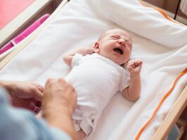 baby crying on a changing table with mom nearby as an example of baby safety tips